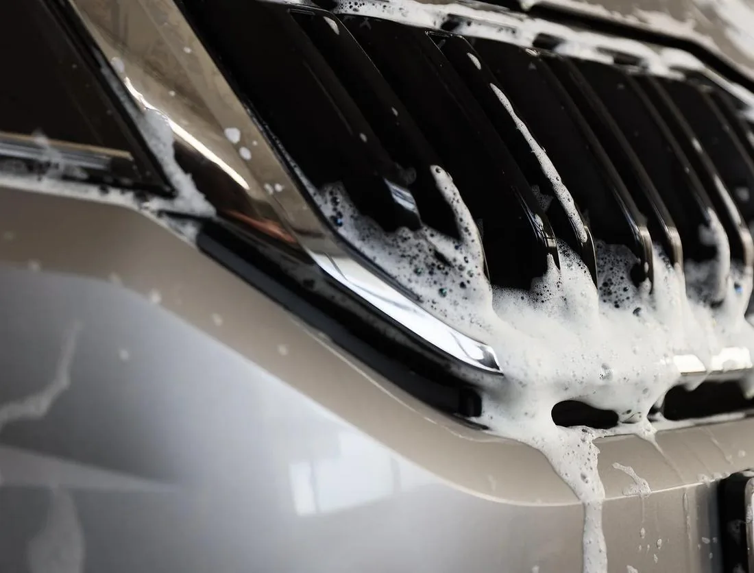 An attendant hand-scrubbing soap into a truck's grille before the tunnel